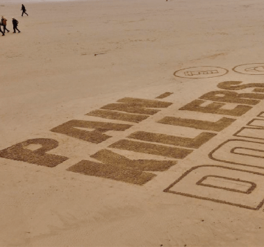 Drone imagery of sand art on a beach as part of the NHS NE&NC ICB: Painkillers Don’t Exist campaign. The art reads: Painkillers Don’t Exist