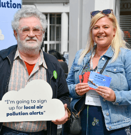A photograph of Michelle Budd and a supporter of the Hertfordshire County Council: Let’s clear the air campaign. They stand together on a highstreet holding campaign materials.