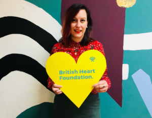 Image of Anna holding a yellow heart sign.