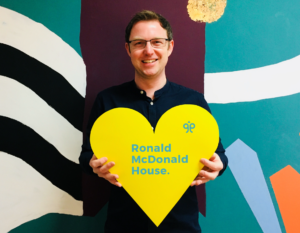 Image of Ged holding a yellow heart sign.