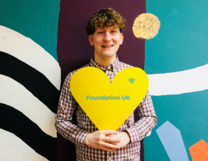 Image of Josh holding a yellow heart sign.
