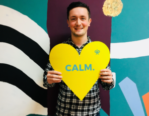 Image of Myles holding a yellow heart sign.