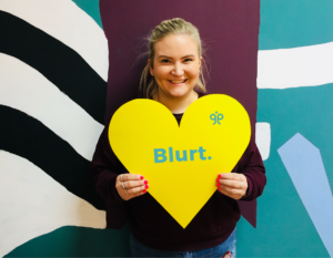 Image of Lizzie holding a yellow heart sign.