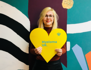 Image of Rebecca holding a yellow heart sign.
