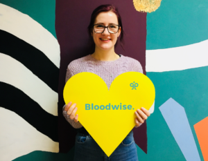 Image of Alice holding a yellow heart sign.
