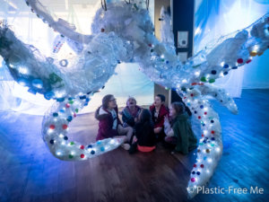 five primary age children sitting underneath a an octopus sculture made from chicken wire and filled with plastic