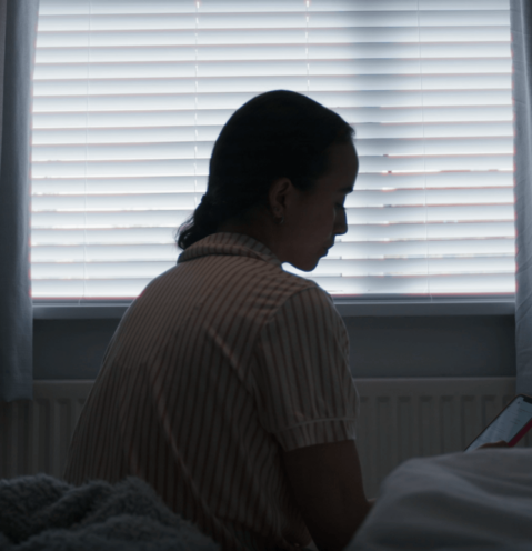 girl looking at her phone silhouetted by her window.