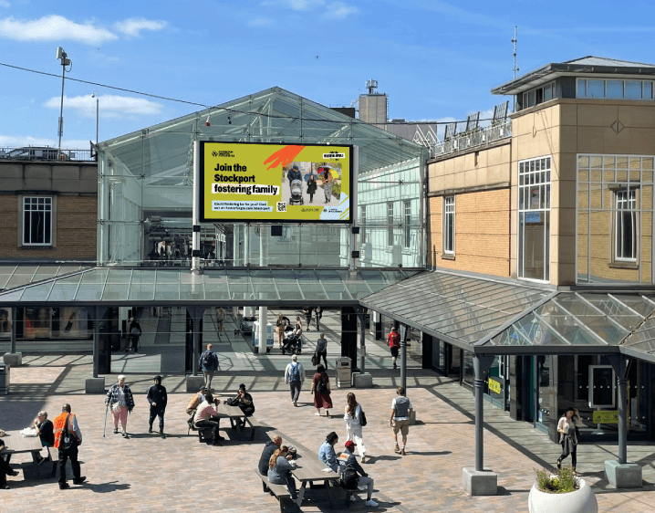 Stockport localised digital out of home screen, at shopping centre with people in the foreground as part of the fostering recruitment campaign.