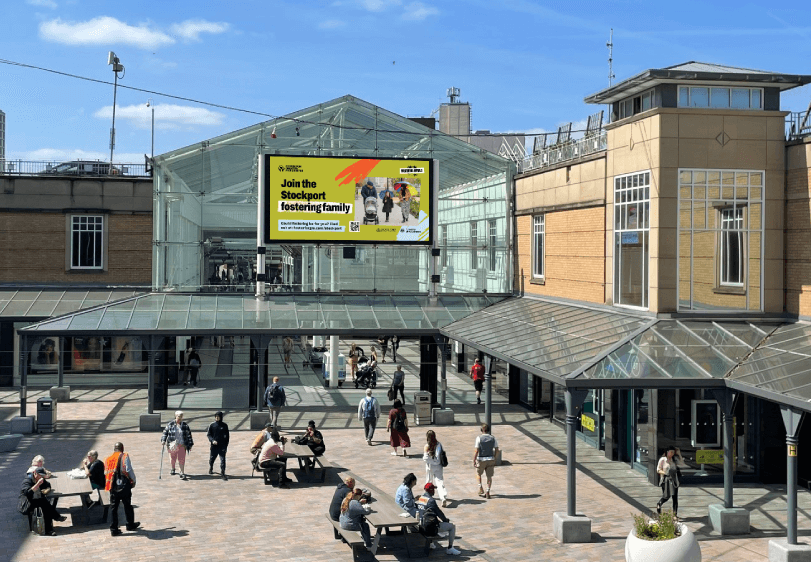 Stockport localised digital out of home screen, at shopping centre with people in the foreground as part of the fostering recruitment campaign.