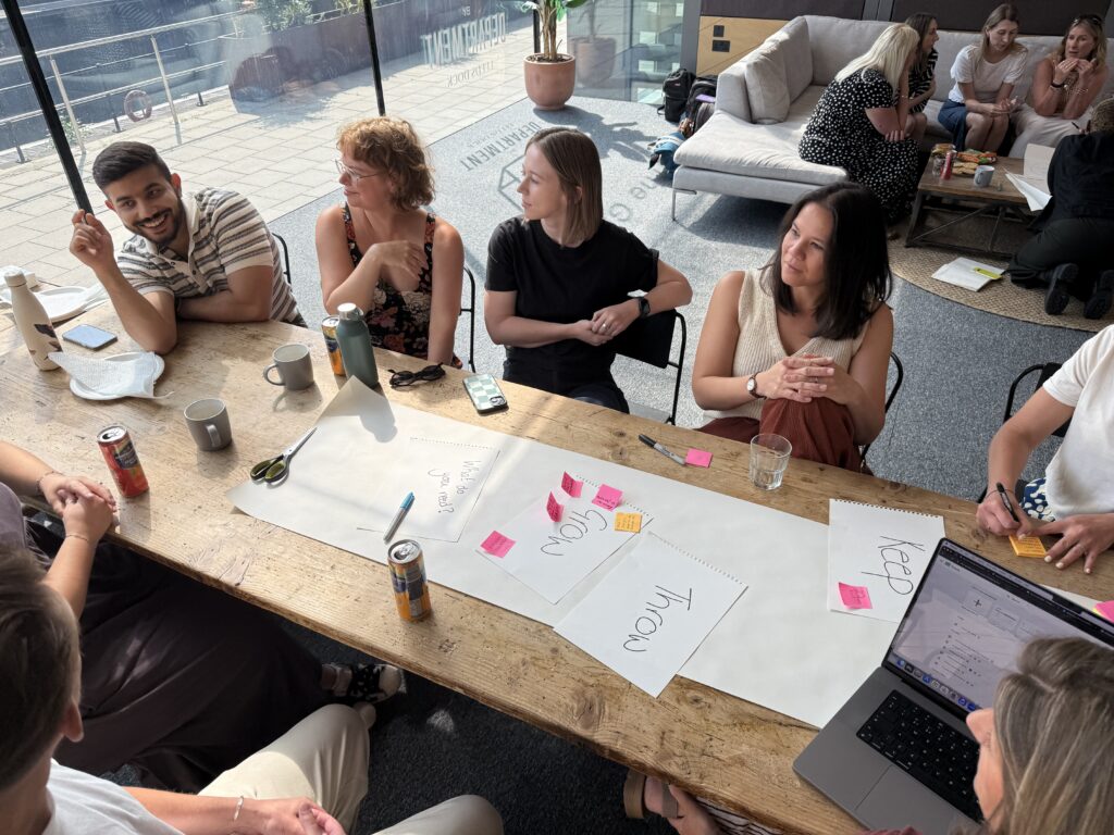 A group of colleagues sat round a table viewing posters and sticky labels